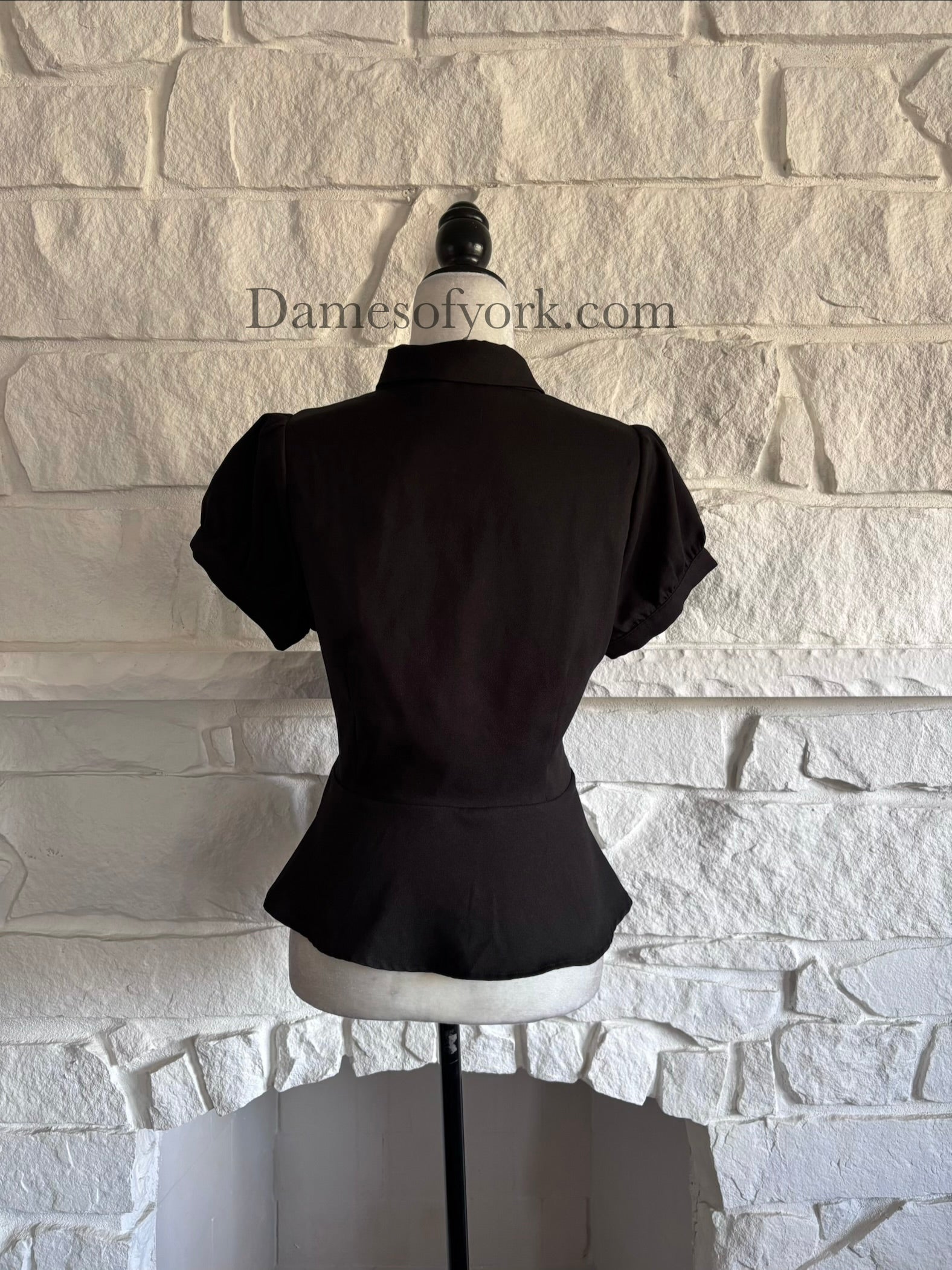 Back view of black long sleeve peplum blouse on mannequin