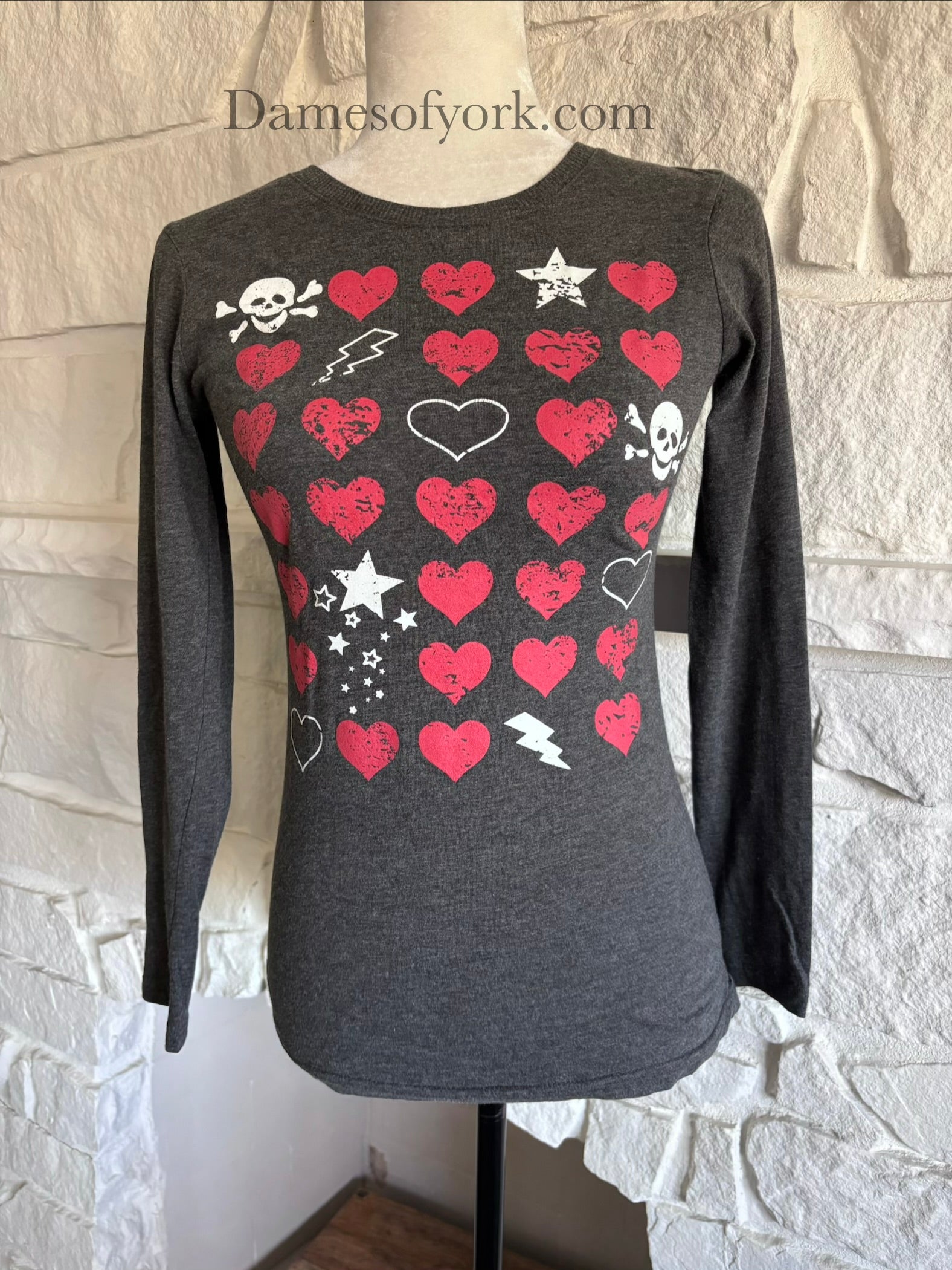 Close up front view of a long-sleeve Y2K inspired t-shirt showcasing the grid pattern of skulls, hearts and lightning bolts.