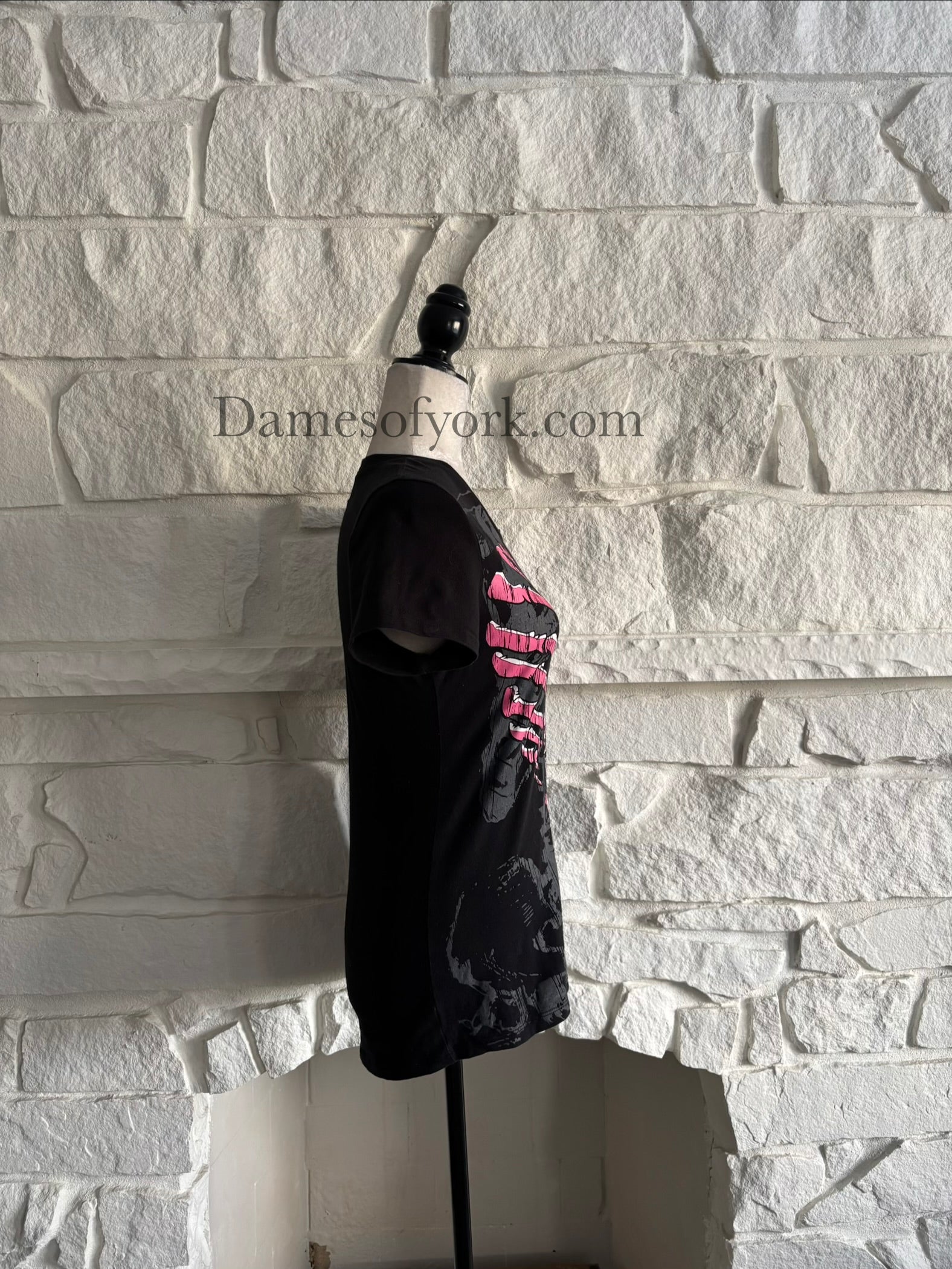 Side view of a black gothic graphic t-shirt featuring a pink ribcage shaped like a heart with printed lace-up detail and a subtle grey skeleton design underneath, styled in an emo-inspired alternative design.