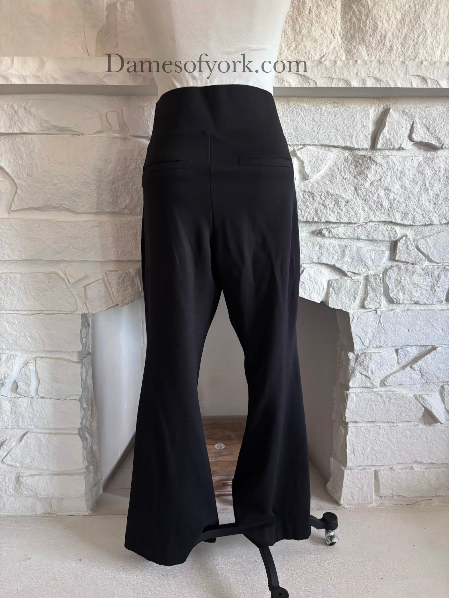 Back view of black wide leg trousers on mannequin with decorative back pockets