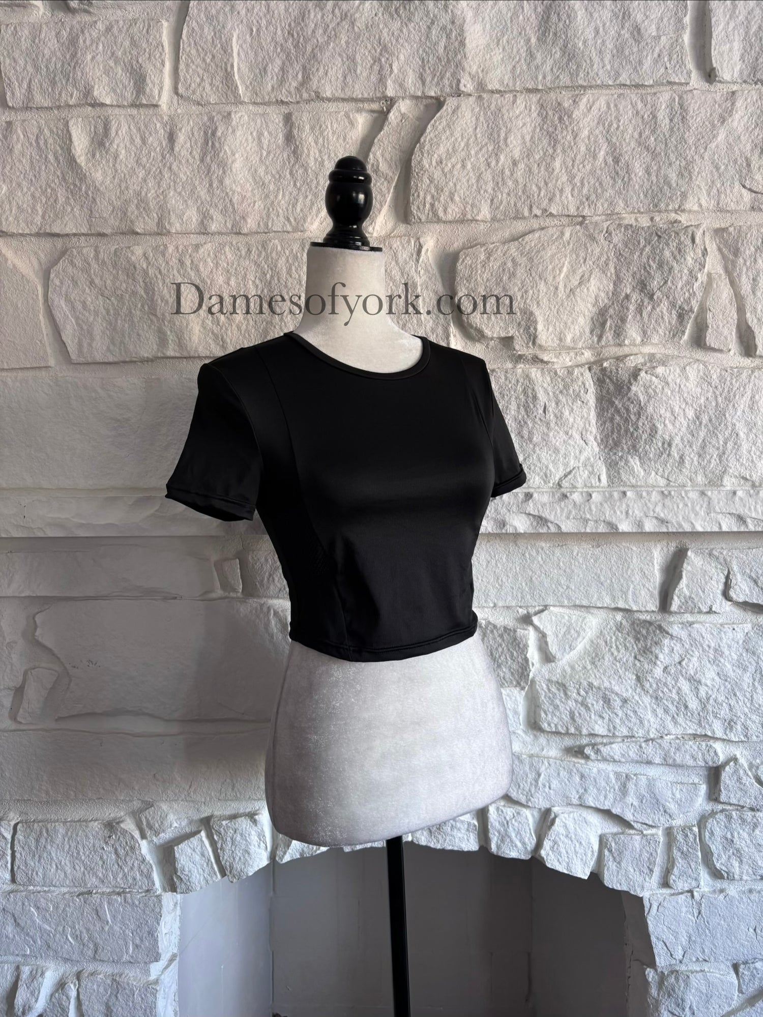 Diagonal view of sleek black performance crop top on mannequin showing fitted silhouette