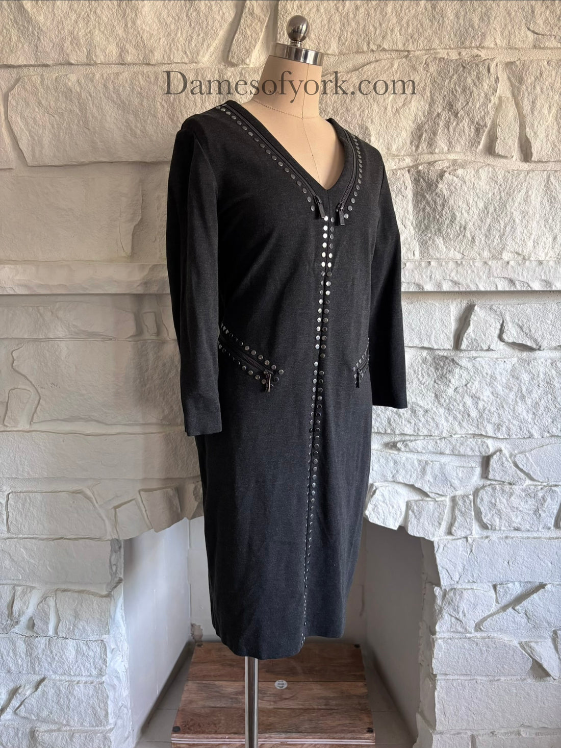 Diagonal view of grey corporate goth dress on mannequin showing V-neck and studded accents