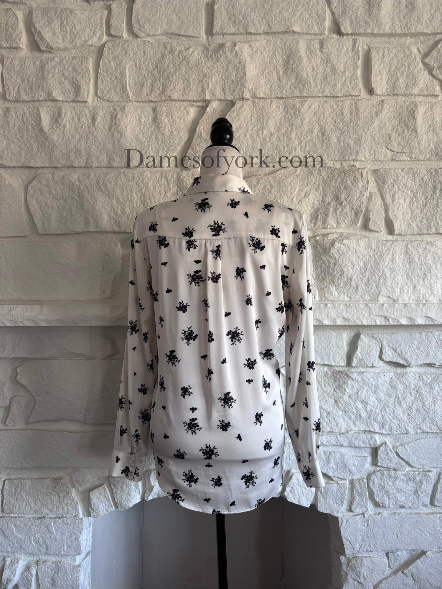 Back view of cream floral button-up blouse on mannequin