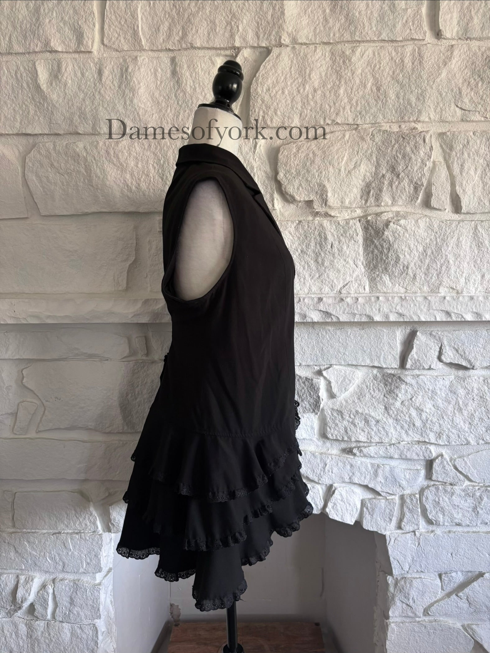 Side view of black steampunk inspired vest on mannequin with layered ruffle trim