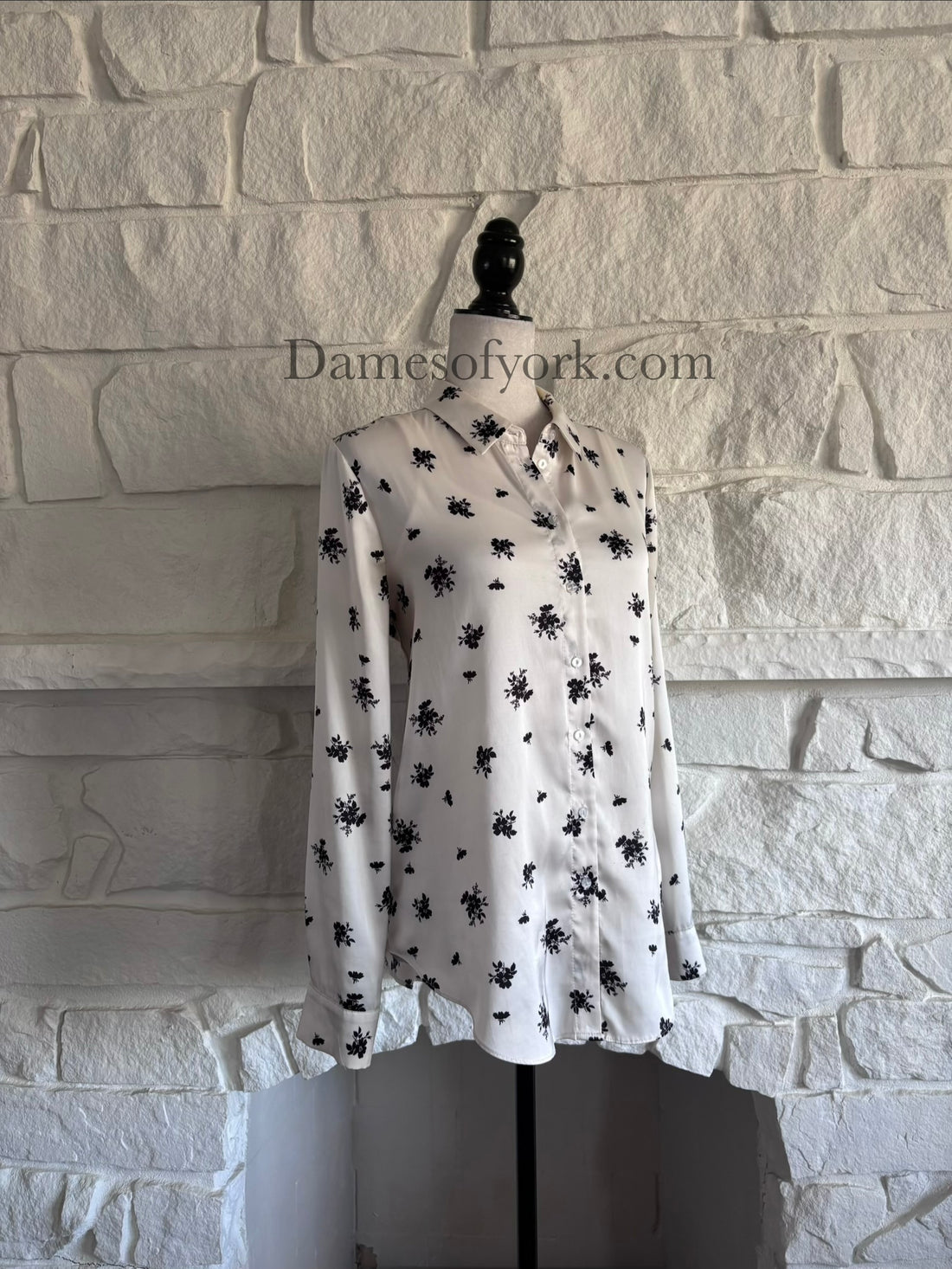 Diagonal view of long sleeve cream gothic blouse on mannequin showing soft drape and floral print