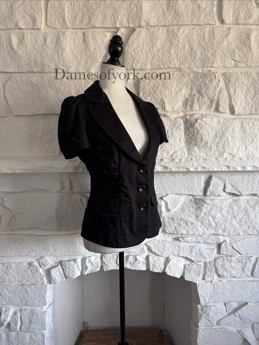 Diagonal view of gothic tailored blazer on mannequin showing curved neckline and puff sleeves