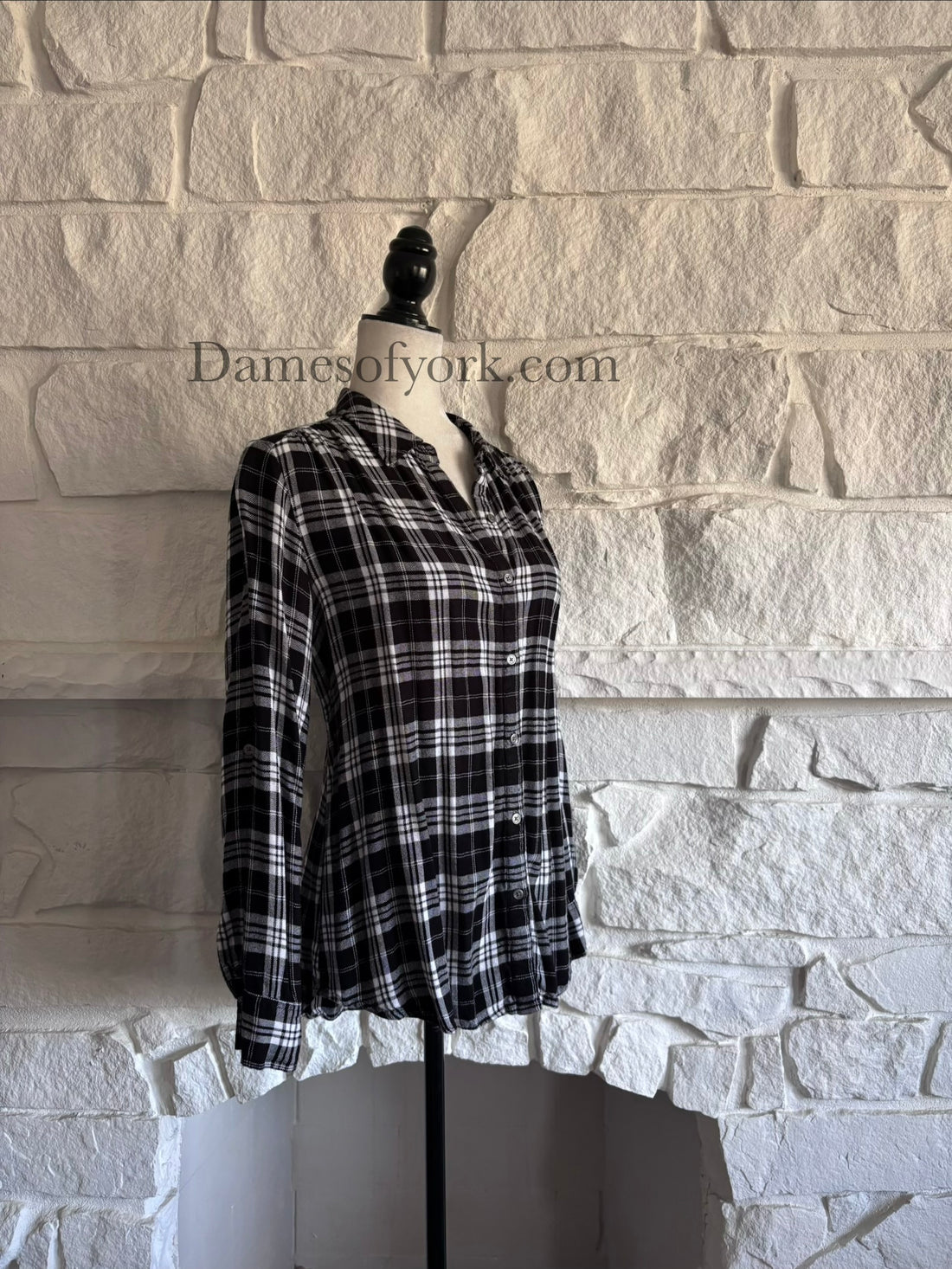 Diagonal view of soft black and white plaid shirt on mannequin showing relaxed silhouette.