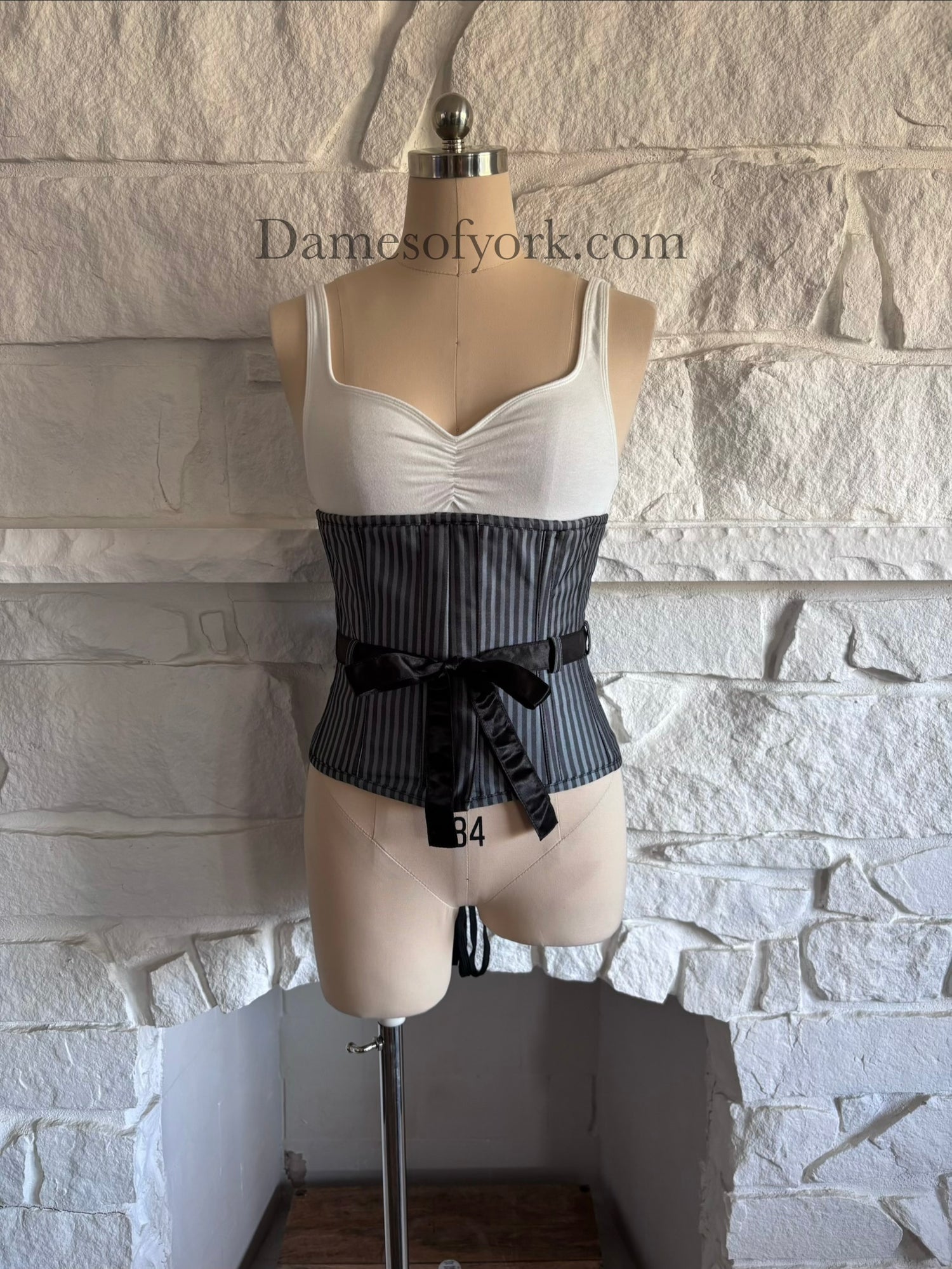 Front view of grey striped steel-boned underbust corset on mannequin with black bow detail