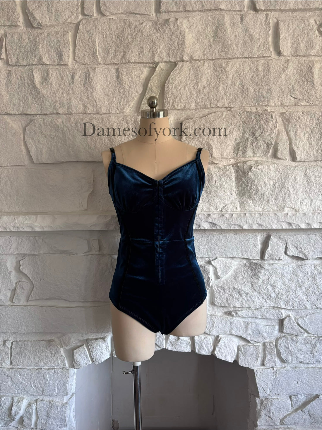 Front view of blue velvet bodysuit on mannequin with hook and eye closure and slimming trim details