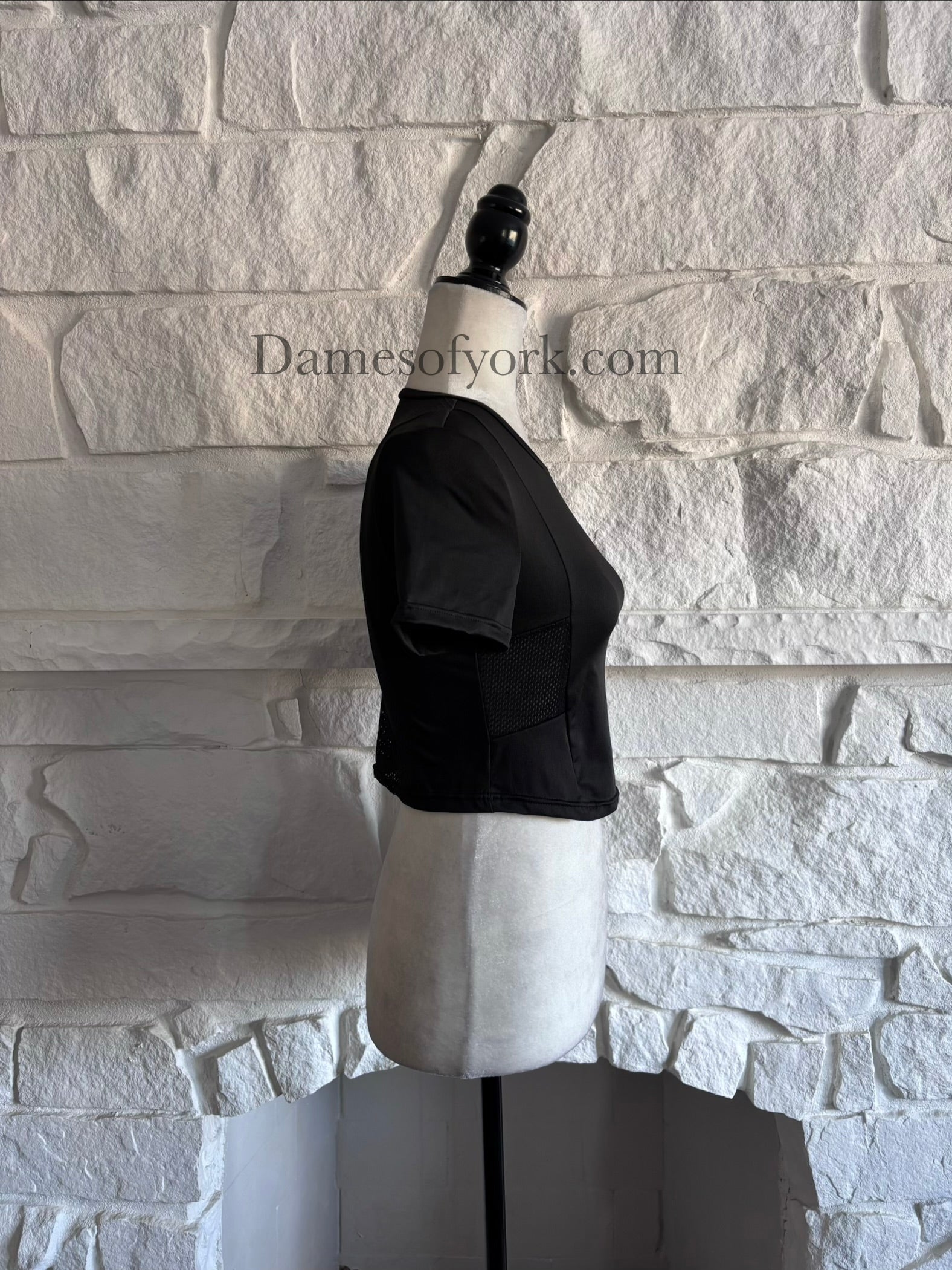 Side view of black stretch athletic crop top on mannequin with ventilation mesh details