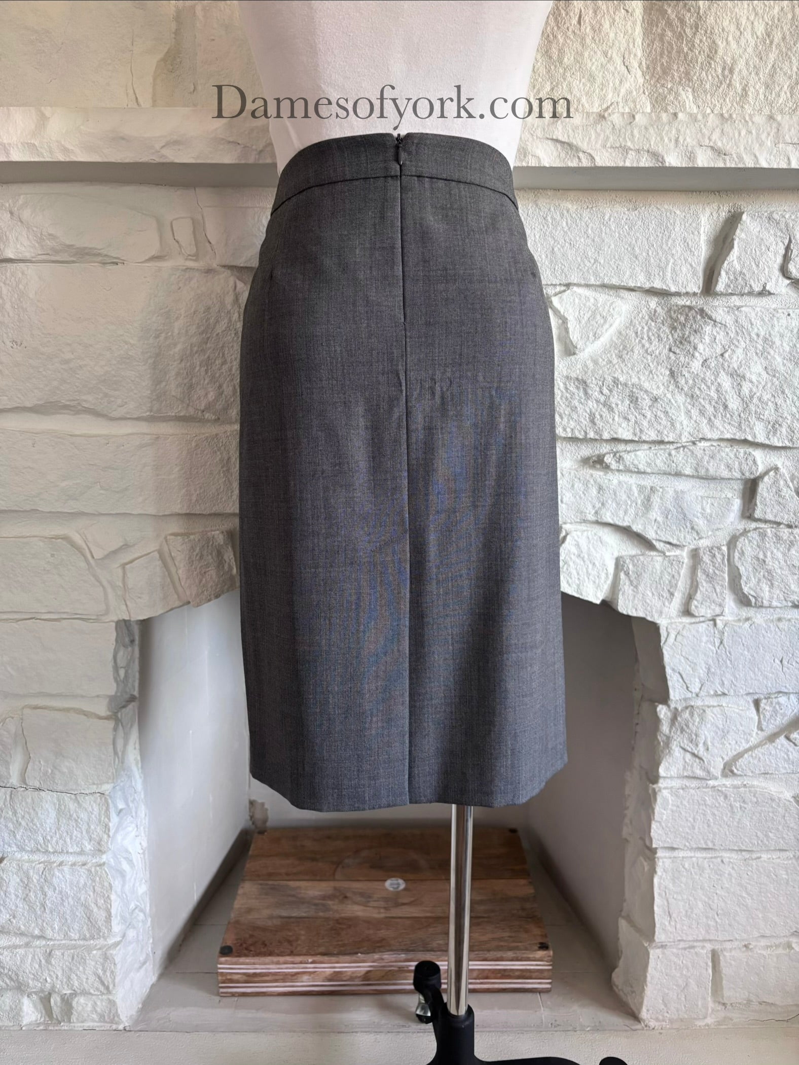 Back view of grey pencil skirt on mannequin with clean structured silhouette