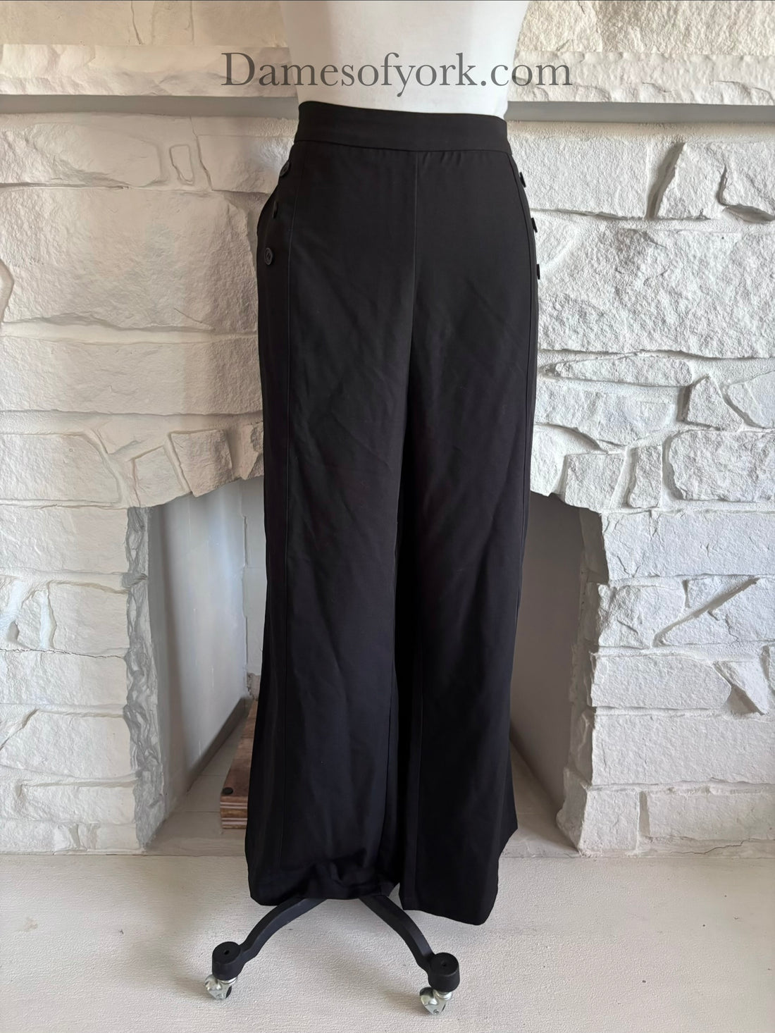 Front view of black wide leg trousers on mannequin with side zip closure and button pocket details