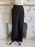 Front view of black wide leg trousers on mannequin with side zip closure and button pocket details