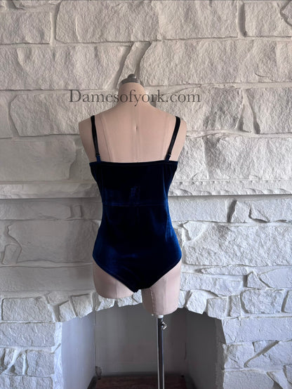 Back view of sapphire blue bodysuit on mannequin with fitted velvet design
