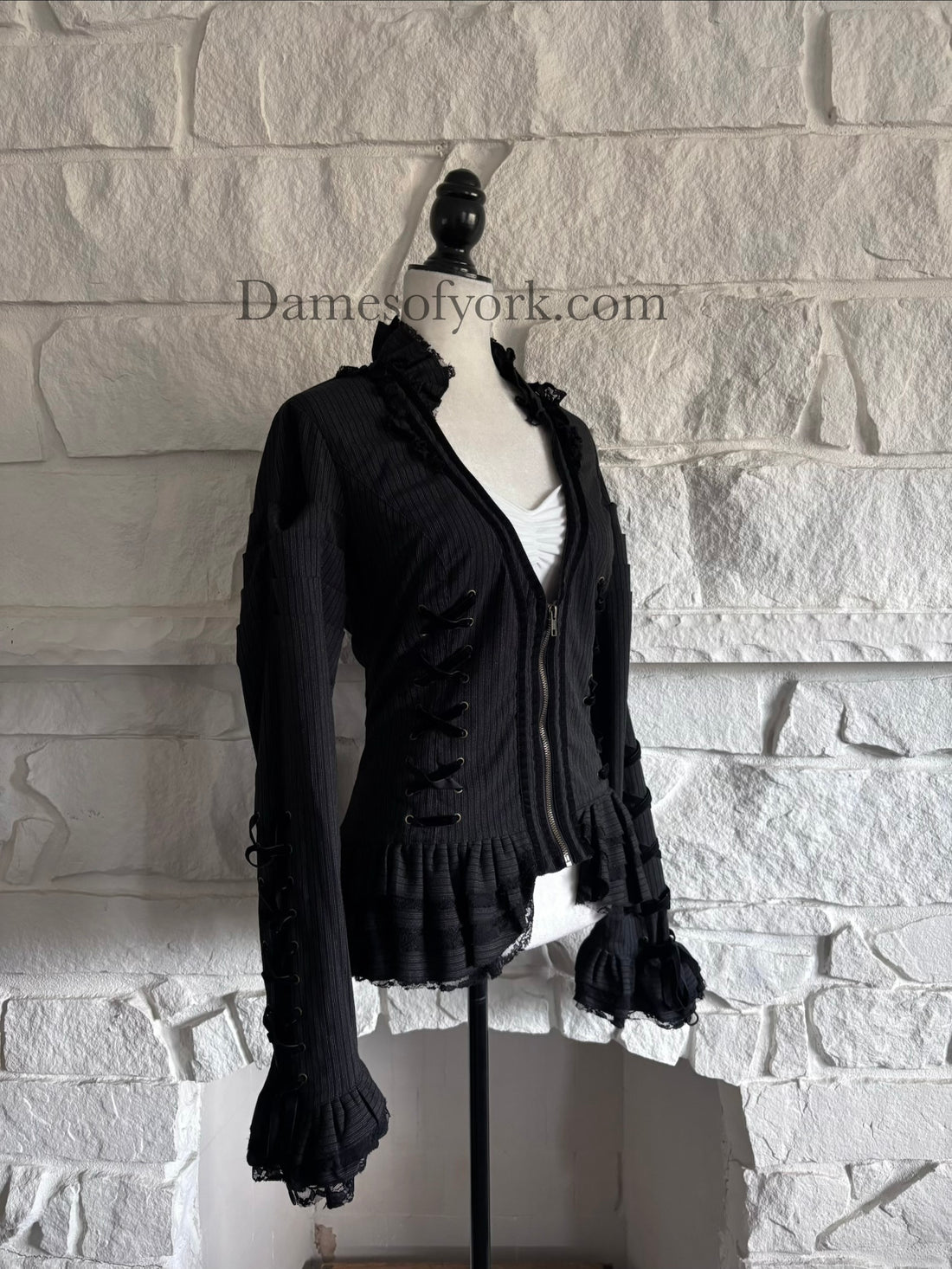 Diagonal view of Victorian style fitted jacket on mannequin showing front lacing and flared lace cuffs