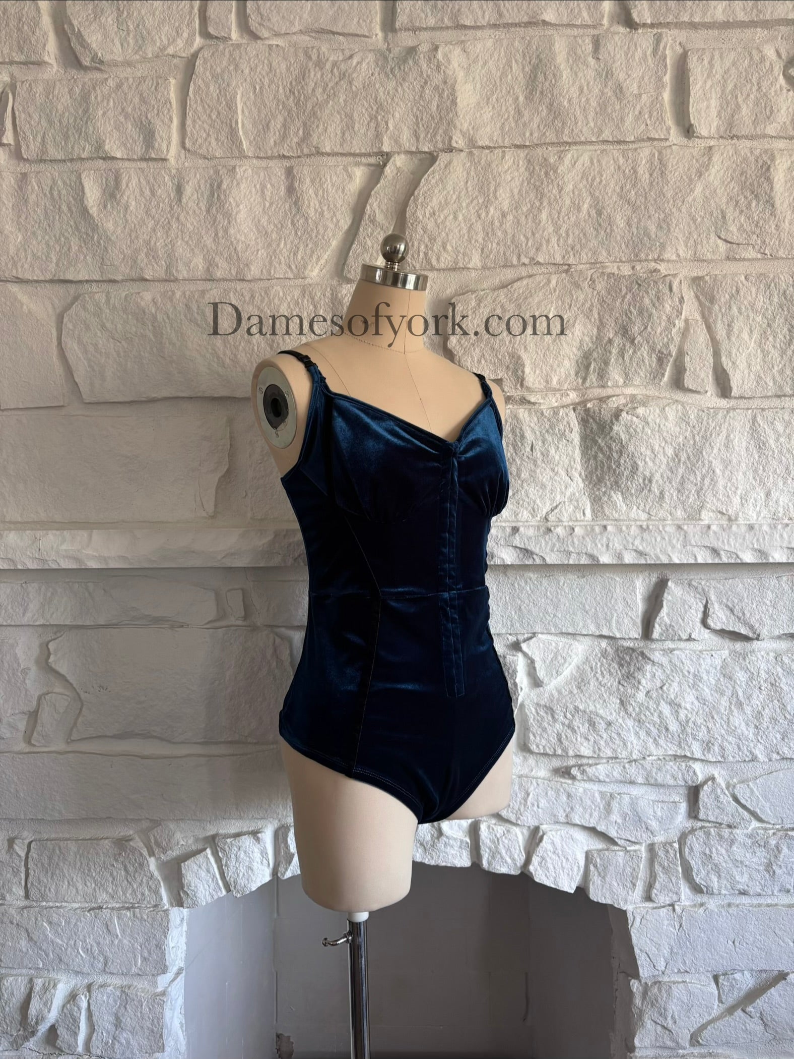 Diagonal view of sapphire velvet fitted bodysuit on mannequin showing sculpted silhouette