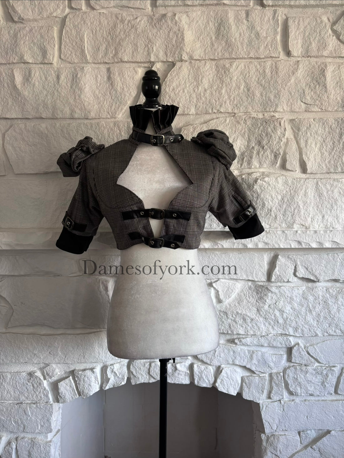 Front view of grey plaid Victorian goth bolero on mannequin with black ruffle collar and buckle details