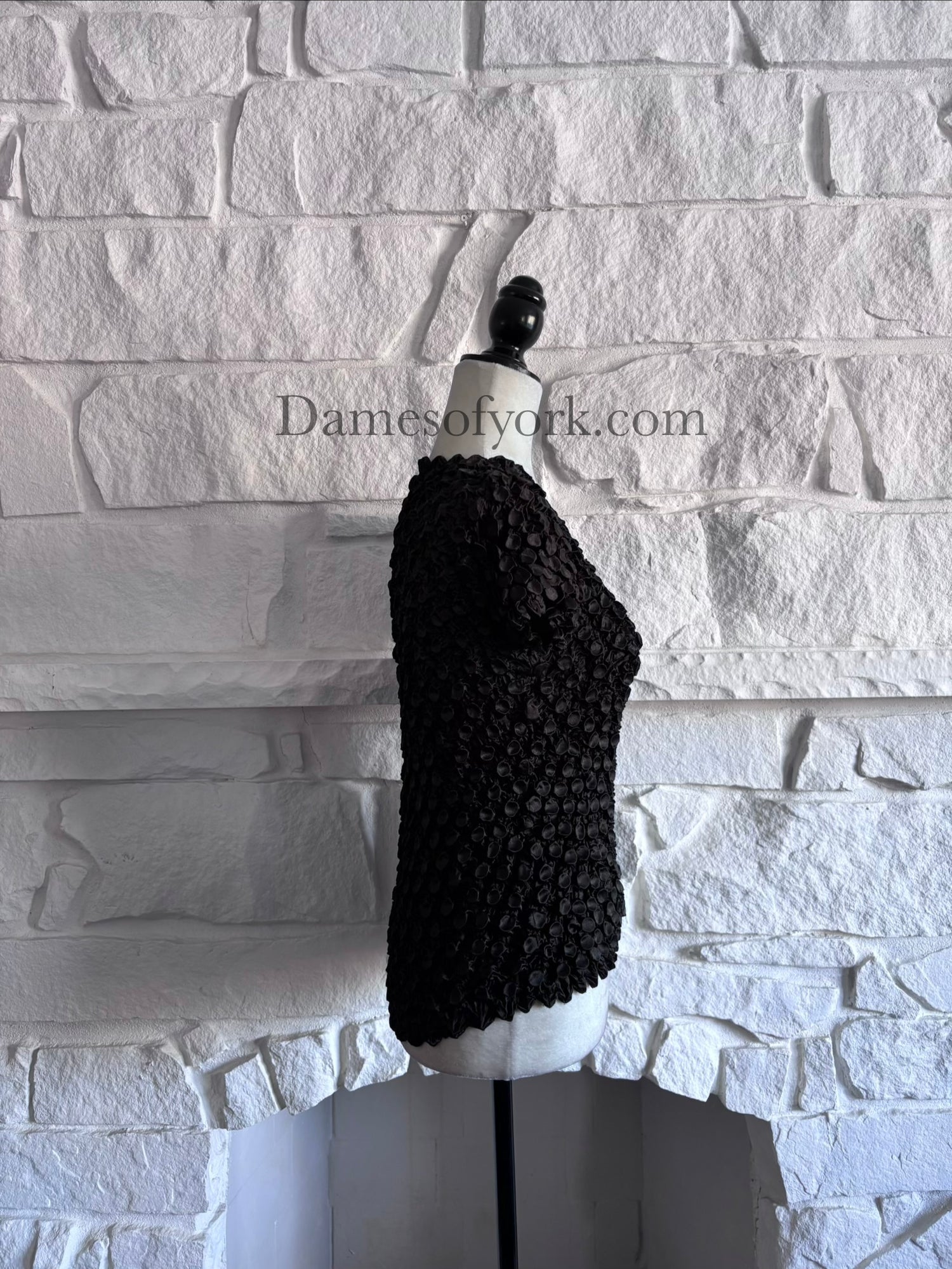 Side view of stretch black textured top on mannequin with organic ripple detailing