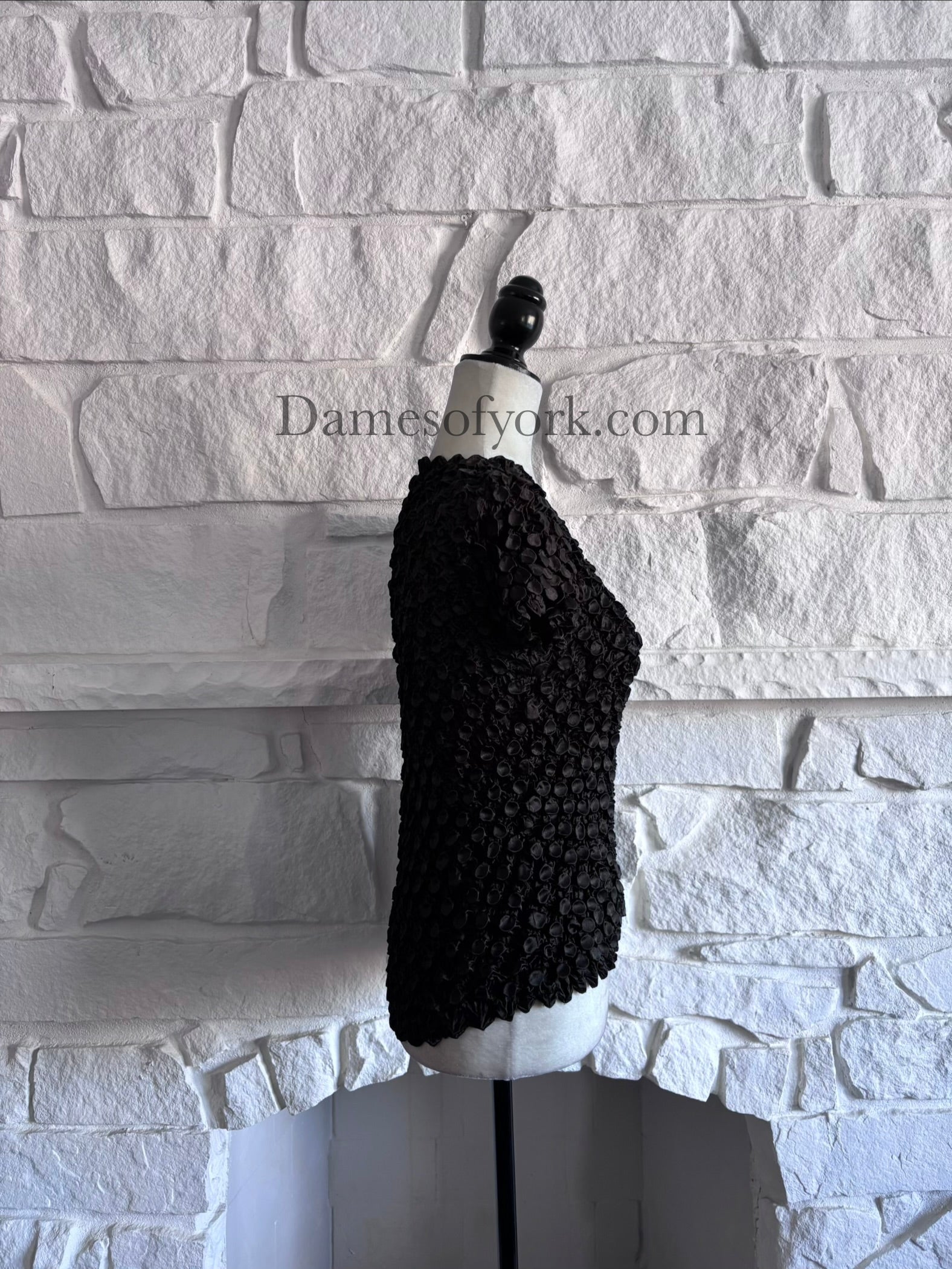 Side view of stretch black textured top on mannequin with organic ripple detailing