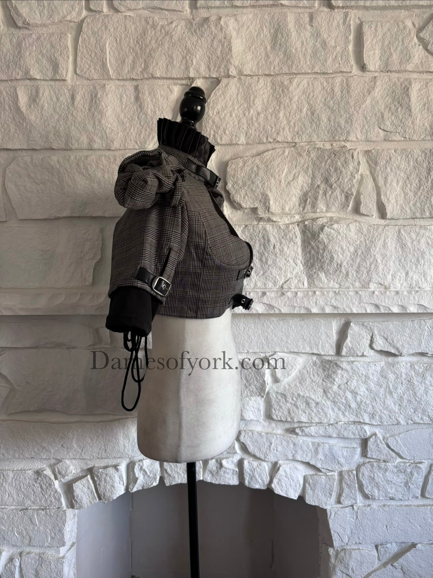 Side view of grey plaid corporate goth bolero on mannequin with layered cuffs and sleeve buckle accents