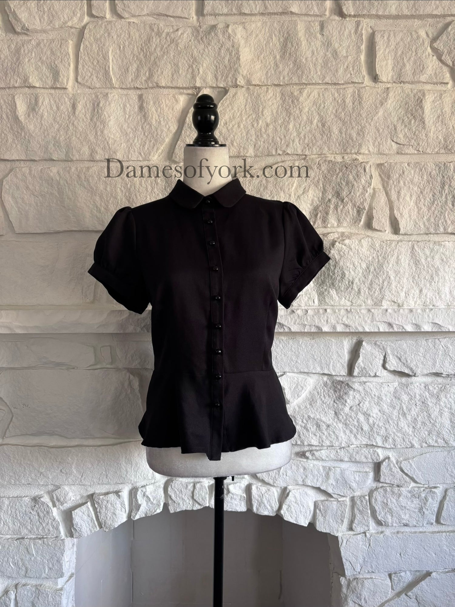 Front view of black peplum button-up blouse on mannequin with Peter Pan collar