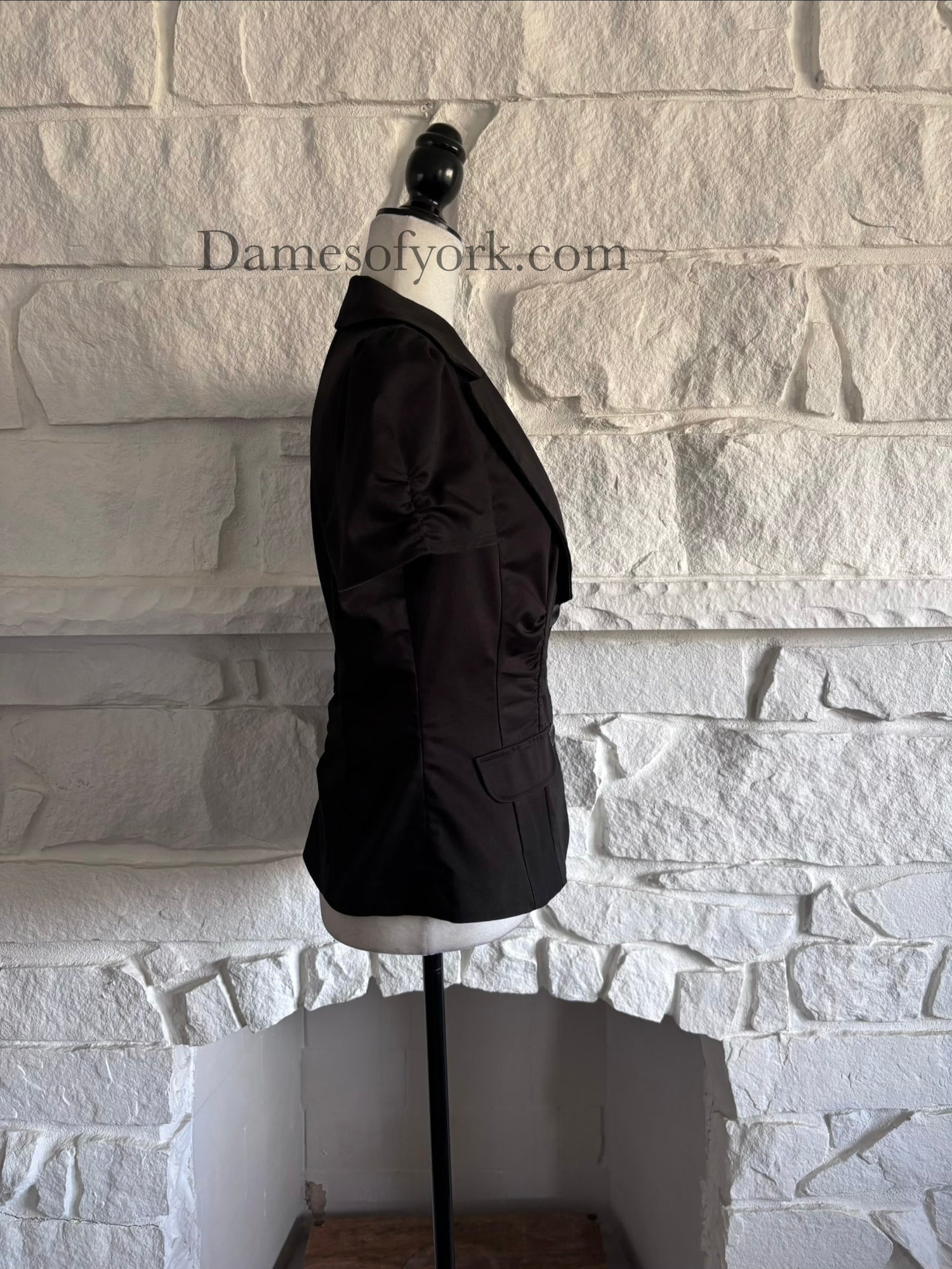 Side view of ruched black blazer on mannequin with fitted waist silhouette