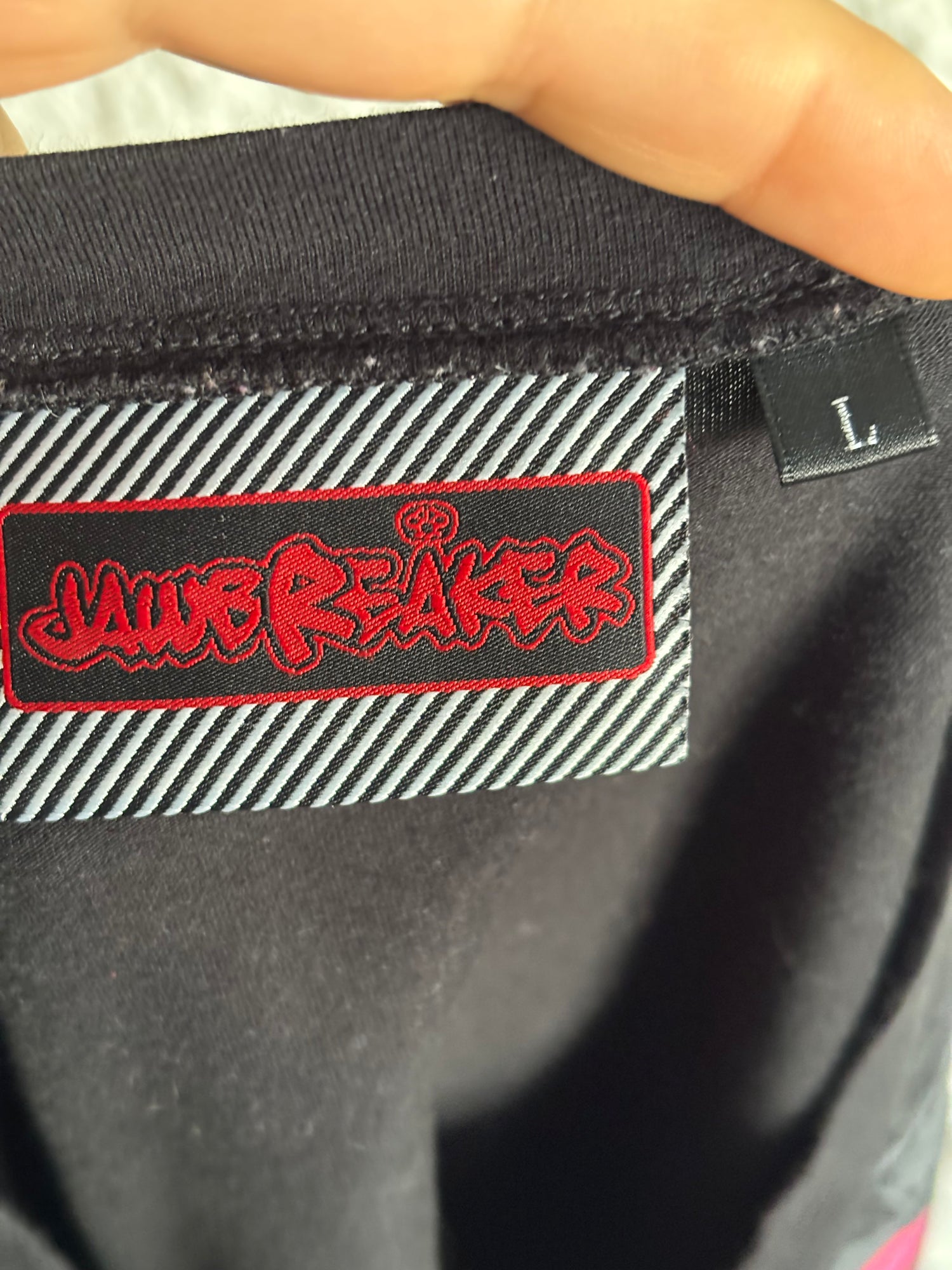 Close-up of a black fabric tag with red and white text for the brand Jawbreaker Clothing.