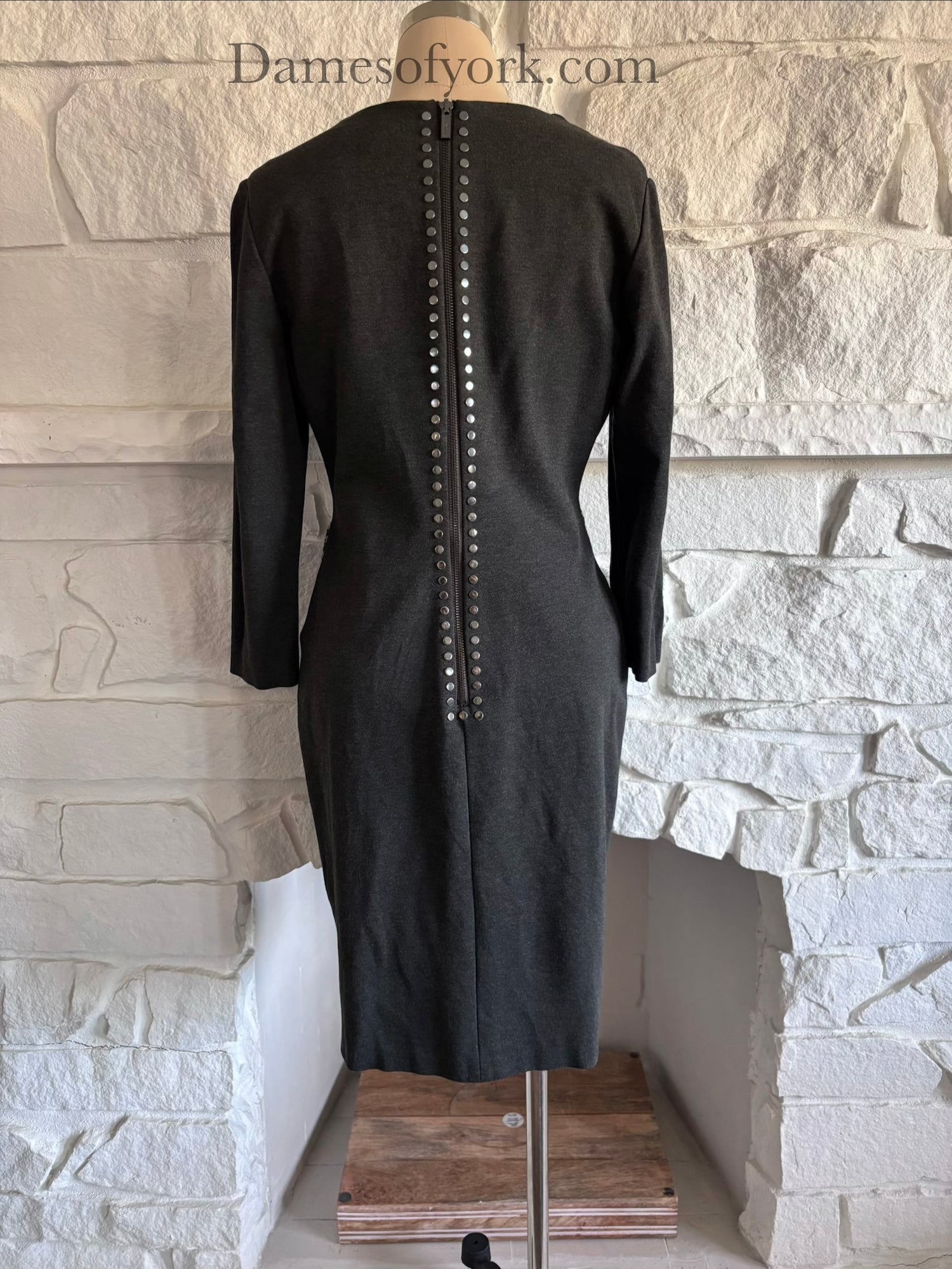 Back view of grey fitted dress on mannequin with zipper closure and studded trim