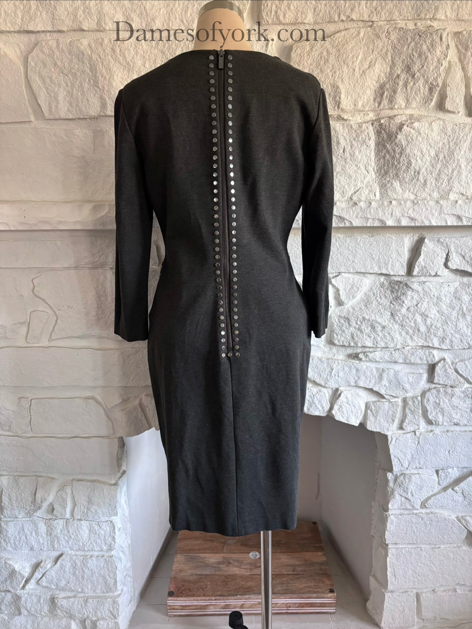 Back view of grey fitted dress on mannequin with zipper closure and studded trim