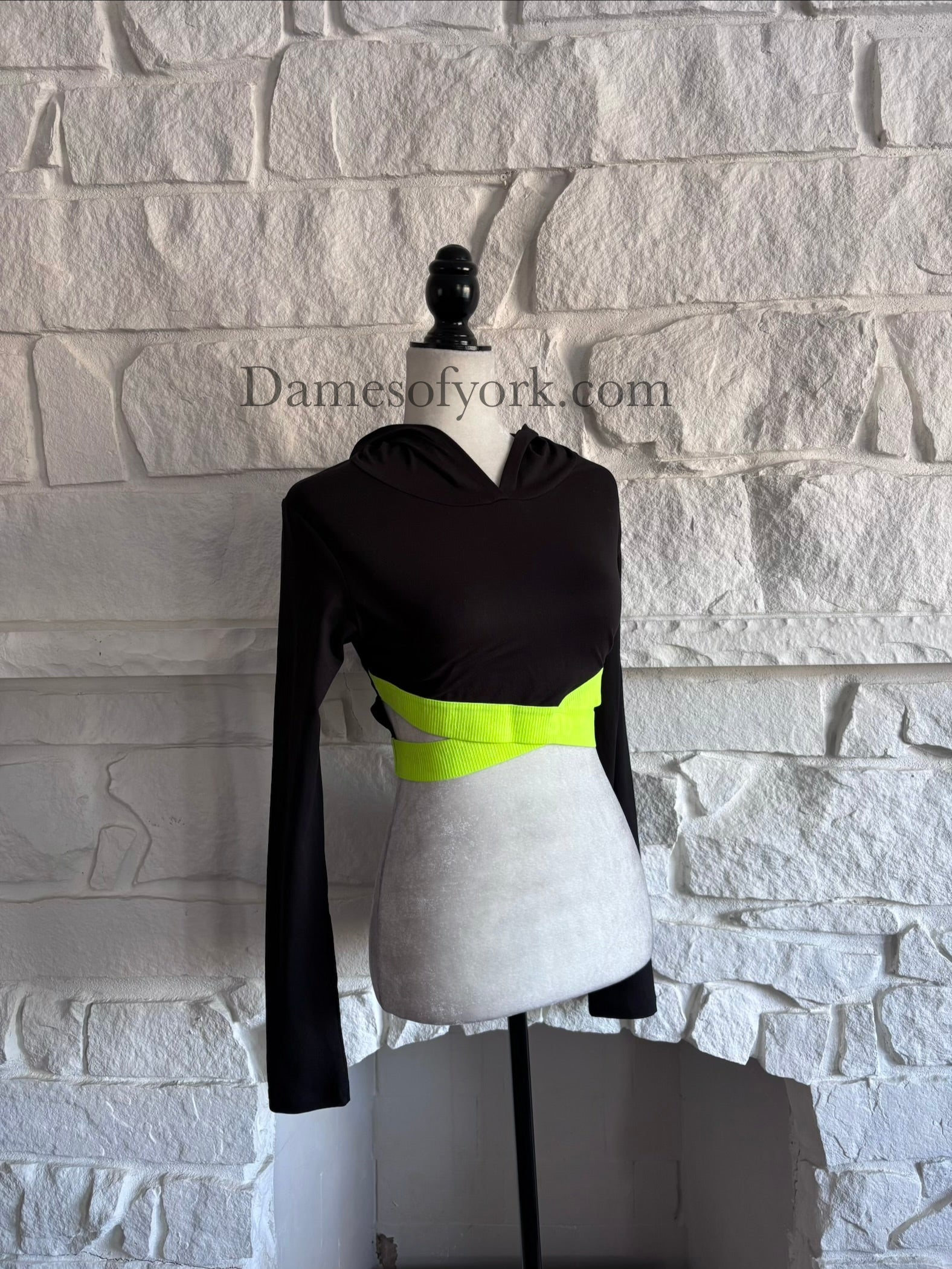 Angled view of the Neon Circuit Crop Hoodie showing the neon yellow criss-cross band design and cropped silhouette.