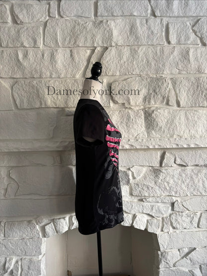 Side view of a black gothic graphic t-shirt featuring a pink ribcage shaped like a heart with printed lace-up detail and a subtle grey skeleton design underneath, styled in an emo-inspired alternative design.