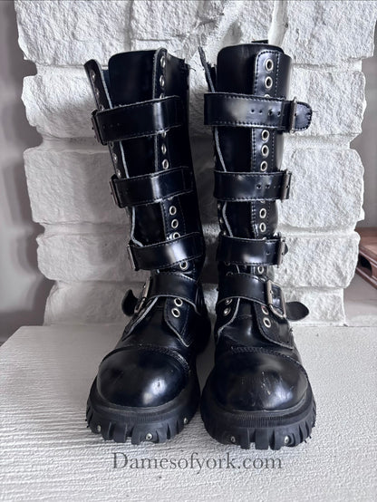 Front view of the Rivet Command Boots, mid-calf black industrial boots with multiple buckle straps and metal grommets.