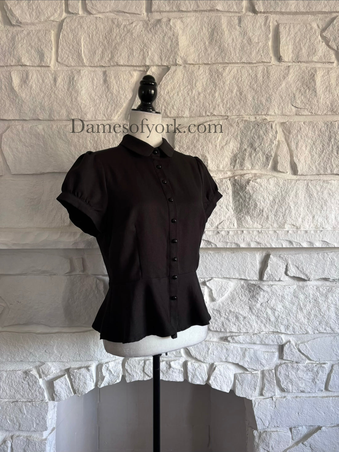 Diagonal view of gothic peplum blouse on mannequin showing fitted waist and puff sleeves