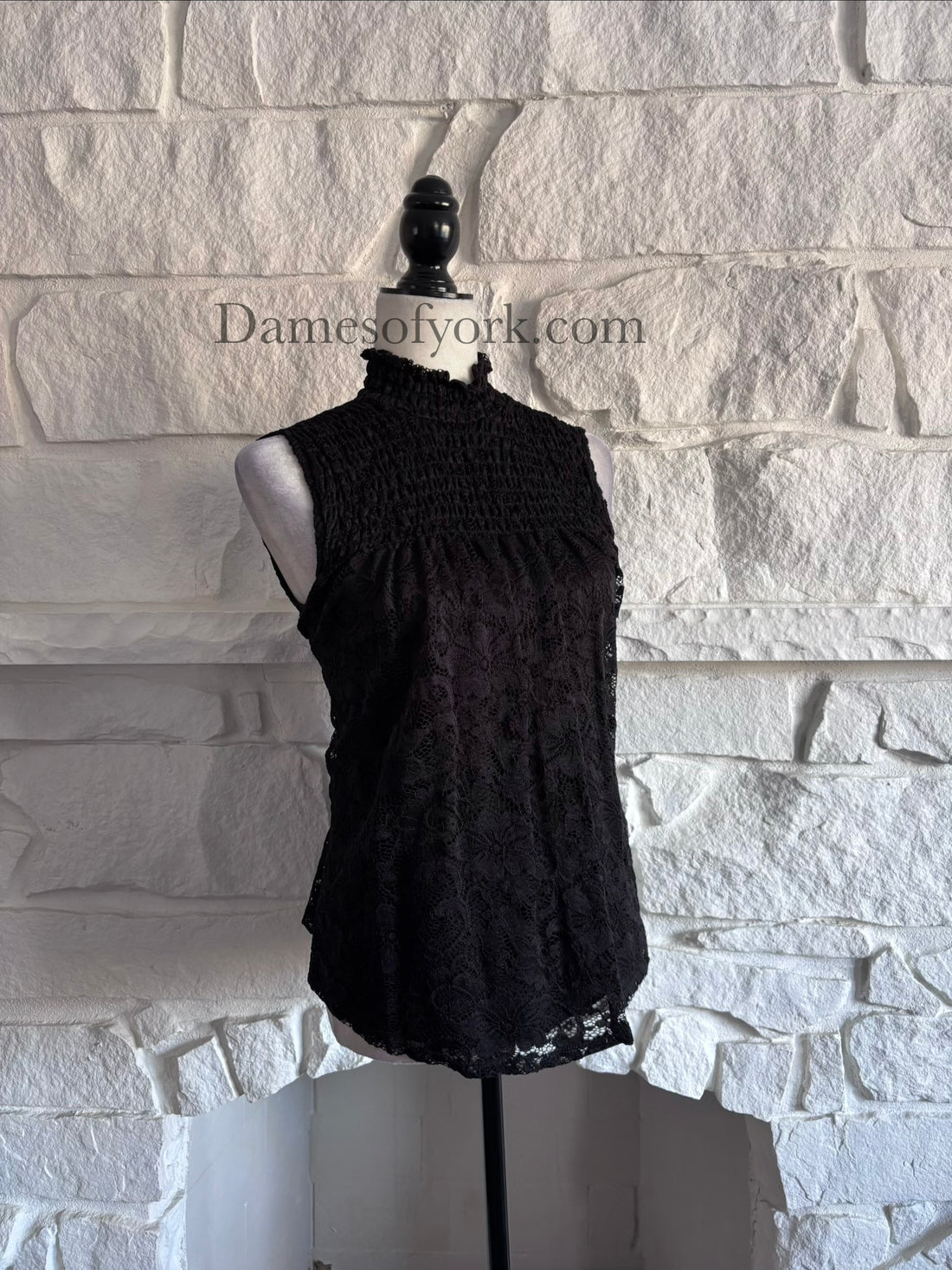 Angled view of the Nocturne Lace Blouse showing the lace overlay texture and high neckline detail.