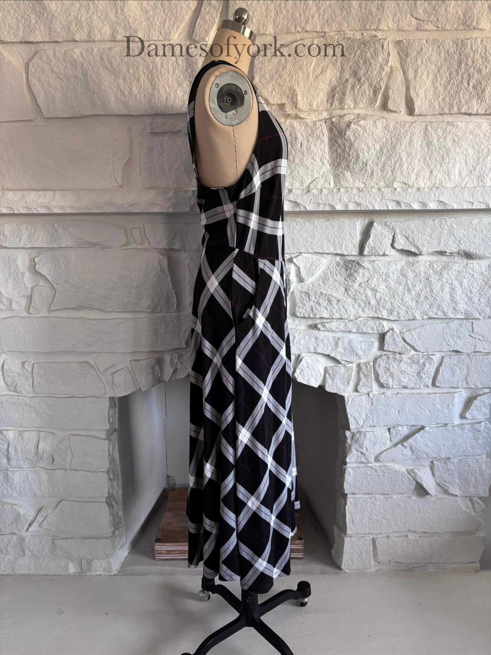 Side view of plaid skater dress on mannequin with fitted waist and flare shape and side pockets
