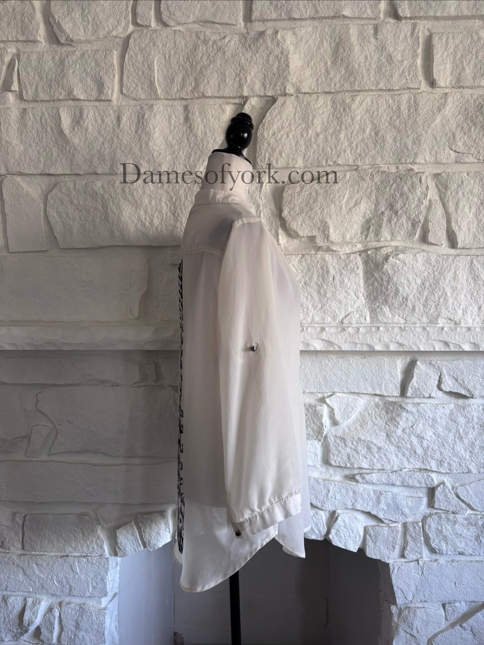 Side view of cream sheer long sleeve blouse on mannequin with loose flowing fabric