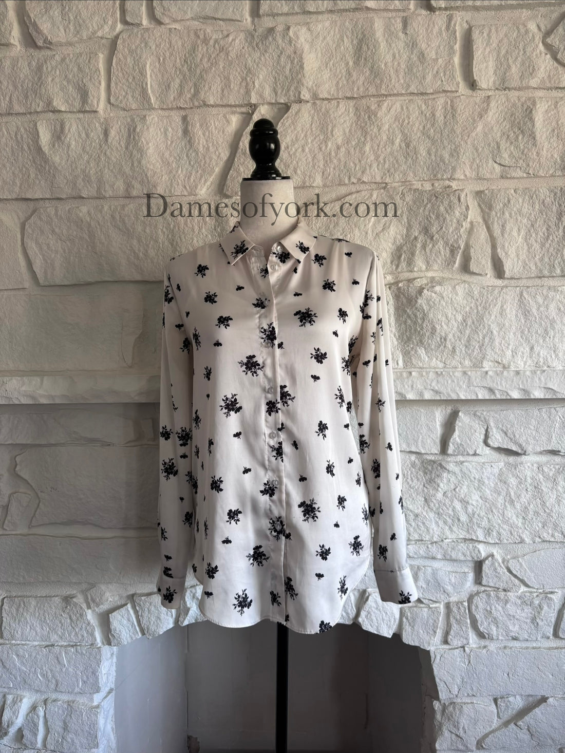 Front view of silky cream button-up blouse on mannequin with black floral pattern