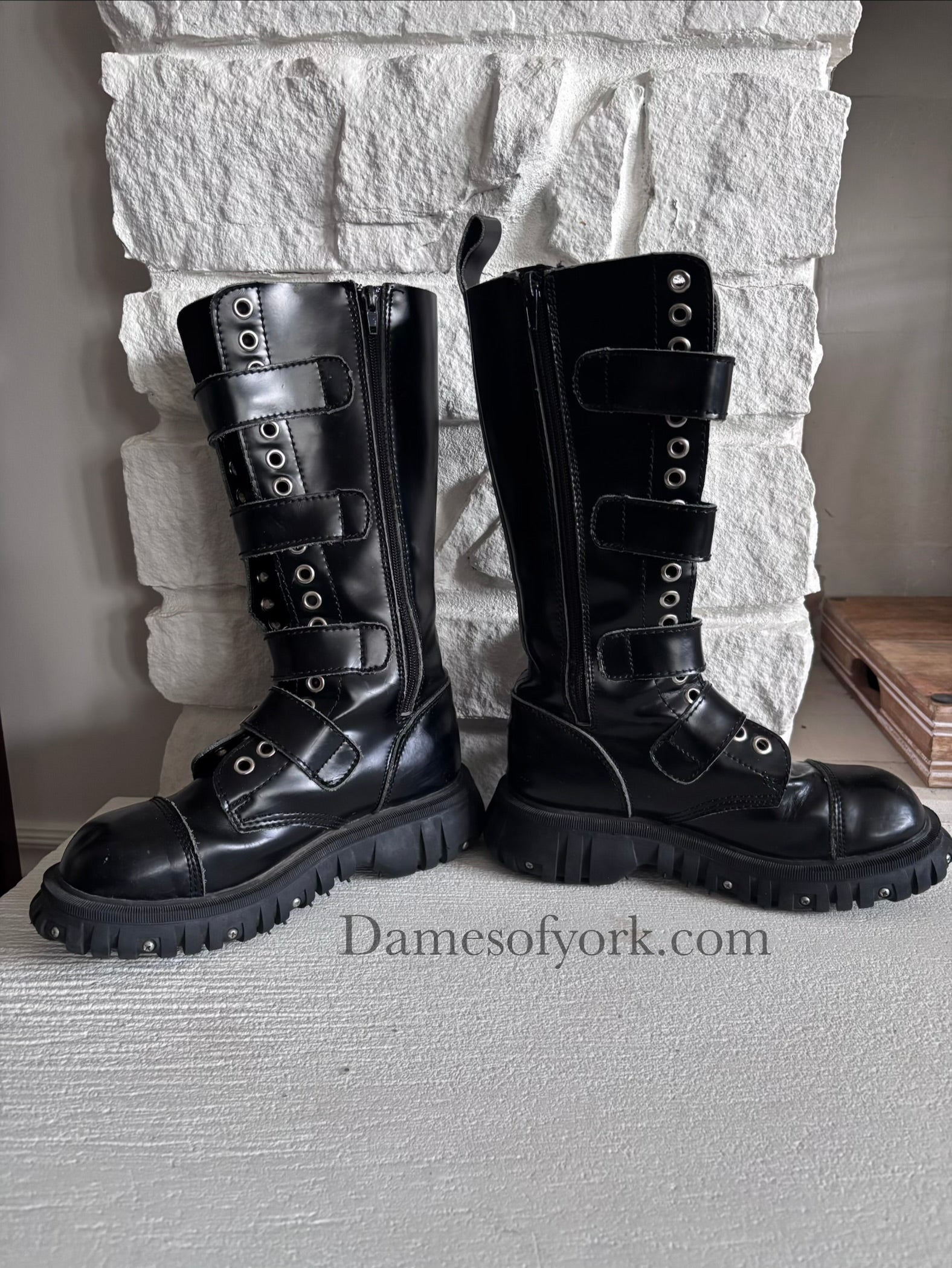 Inside view of the Rivet Command Boots (inner right and left), mid-calf black industrial boots with multiple buckle straps and metal grommets with inner zipper closure.