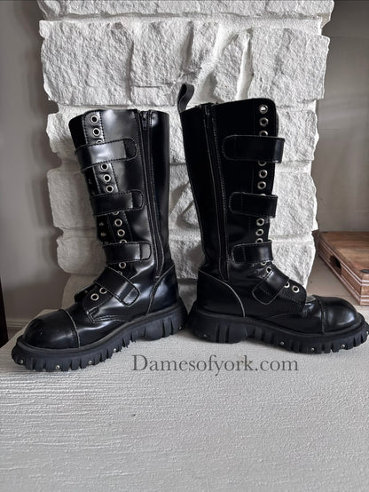 Inside view of the Rivet Command Boots (inner right and left), mid-calf black industrial boots with multiple buckle straps and metal grommets with inner zipper closure.